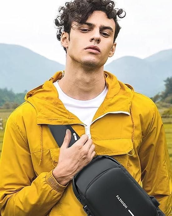 Man in a yellow jacket holding a black bag with mountains in the background