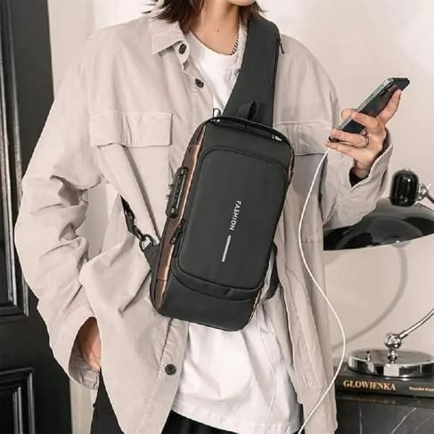 Person wearing a black crossbody bag holding a phone, with a car and door in the background.
